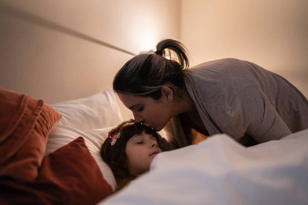 Mother putting daughter to sleep at home Mother putting daughter to sleep at home bedtime stock pictures, royalty-free photos & images