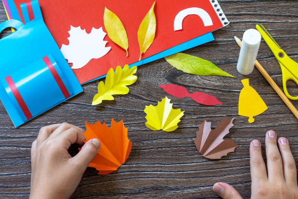 istock Instruction step 8. Greeting card paper backpack on a wooden table. Handmade. Project of children's creativity, handicrafts, crafts for kids. 1328363012