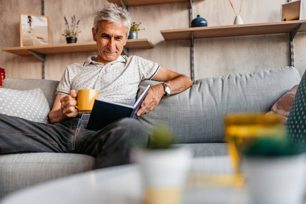 istock Senior man relaxing at home and reading a book 1328363896