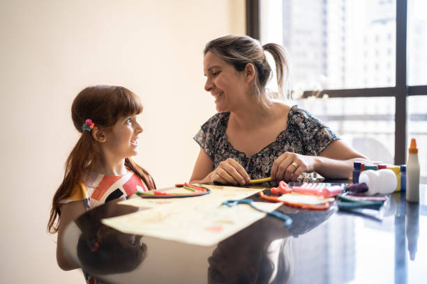 istock Mother helping daughter with arts project at home 1328364723