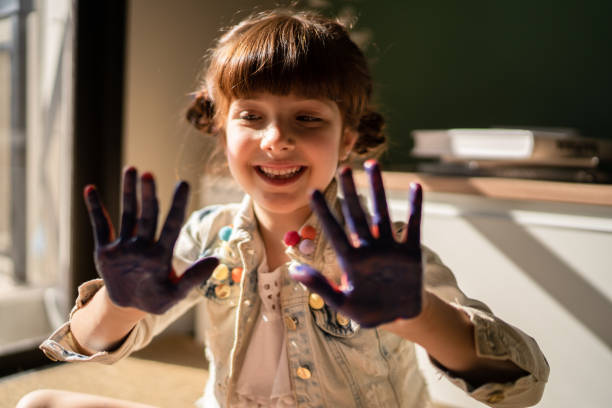 istock Cute girl showing hands covered in paint 1328365438
