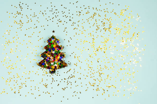 istock Christmas tree baking mold with colorful sparkles inside on a light blue background. Flat lay. View from above. Place for an inscription. Base for a postcard. 1328367668