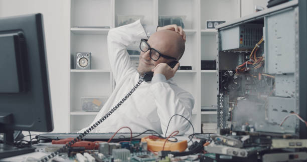 Computer failure in the technician office Distracted computer repair technician having a phone call while the computer is short-circuiting Distracted stock pictures, royalty-free photos & images