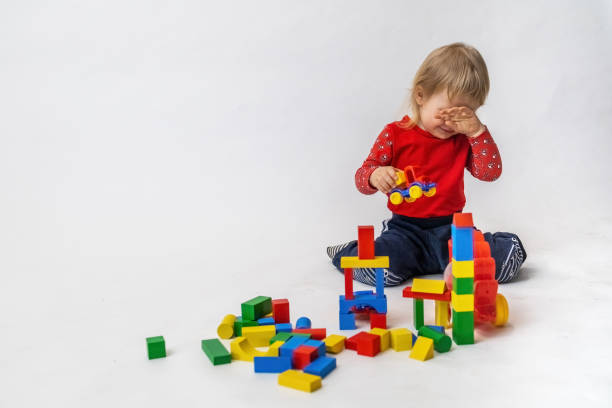 istock Crying little boy is playing with colorful wooden cubes 1328369909