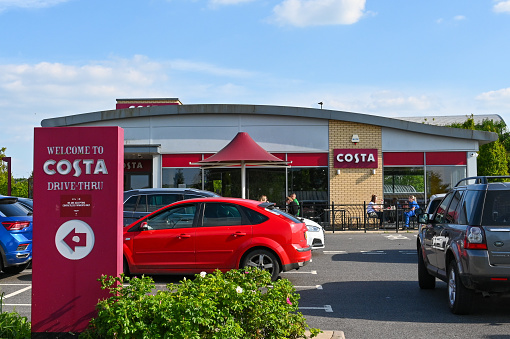 Andover, England - June 2021: People and cars outside a drive-thru branch of Costa Coffee