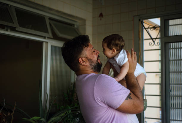 istock Dad playing with baby in his lap. 1328370617