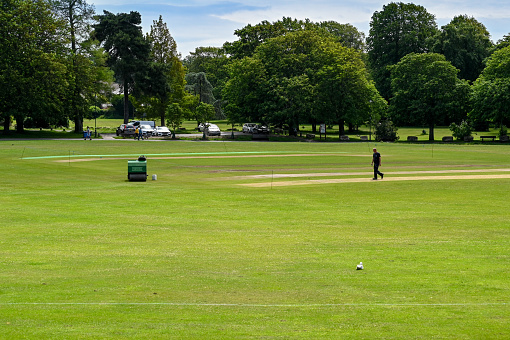 Poole, Dorset, England - June 2021: Groundsman working on a cricket pitch in a public park in Poole..
