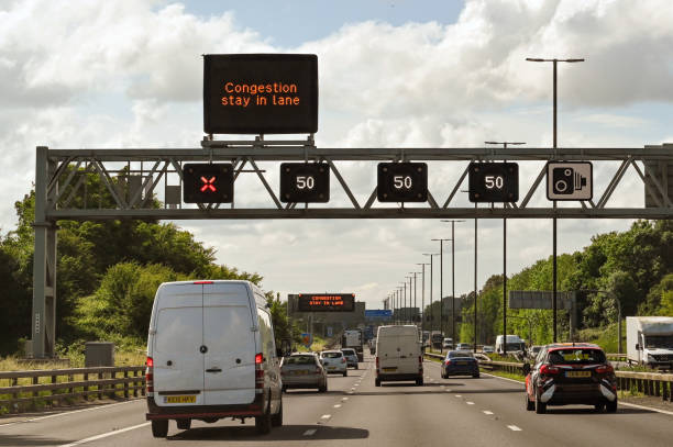 Overhead gantry on a motorway with digital speed and lane closed signs Bristol, England - June 2021: Overhead gantry on the M4 motorway with road signs showing the speed limit and a closed lane. traffic car traffic jam uk stock pictures, royalty-free photos & images