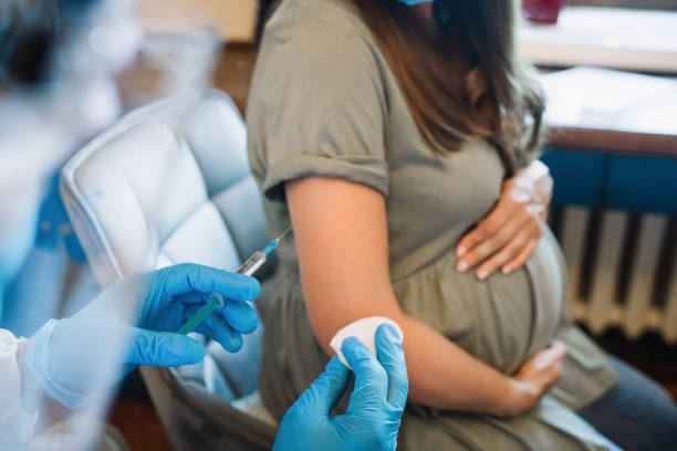 Doctor/nurse giving vaccine injection to pregnant woman Pregnant woman getting vaccine at home. COVID-19 vaccination concept. pregnant stock pictures, royalty-free photos & images