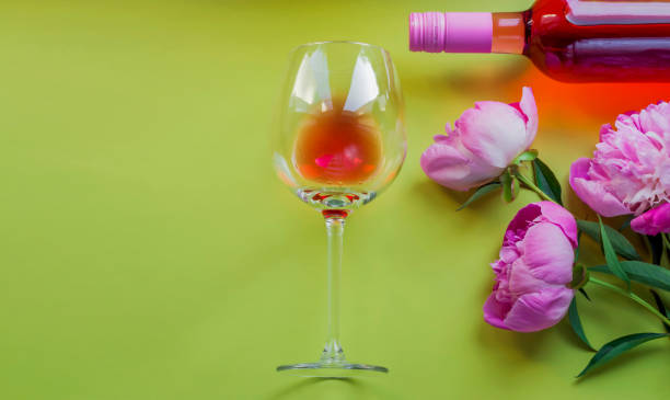 istock Creative summer composition with rose wine in a large glass and beautiful peonies on a green background. Happy Mother's Day, International Women's Day. Valentine's Day. Copy space. Flat lay 1328371917