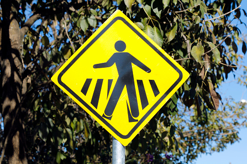 Orange sign showing a black arrow and black pedestrian symbol