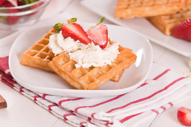 Waffles with strawberries and whipped cream.