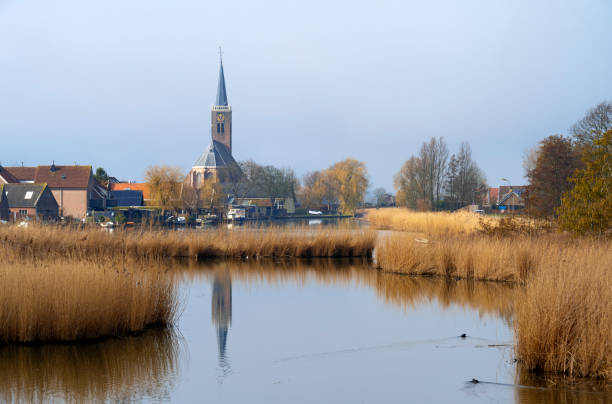 Typical Dutch village houses and a church in a small village along a canal in the Netherlands. Location is Schermerhorn, Netherlands.