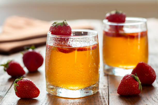 Homemade lemonade with strawberries. Summer cold drink. A pair of glasses of kombucha with additional flavors on wooden table. Tasty healthy beverage.