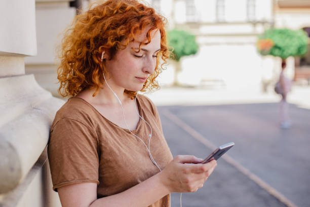 istock Redhead woman is using mobile phone outdoors 1328380400