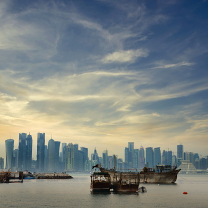 Doha skyline with arabic style Dhow boats in the foreground Just before sunset in Doha, Qatar