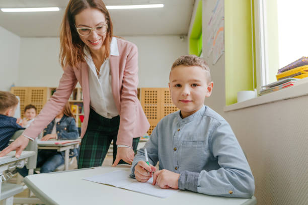 istock Female teacher helping schoolboy in the classroom 1328381740