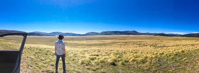 Man Outside Car Admiring Valles Caldera Wilderness, NM Panoramic