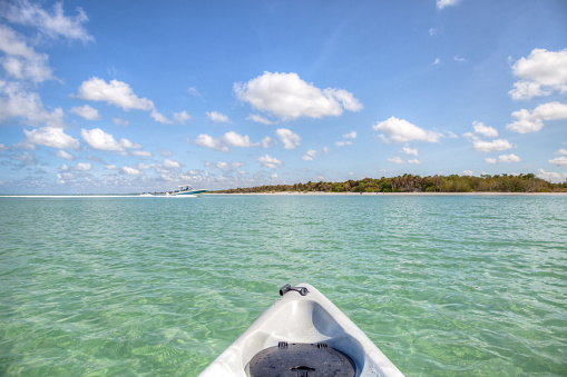 Speed boat in front of Kayak on crystal clear ocean water of Delnor Wiggins State Park of Naples, Florida