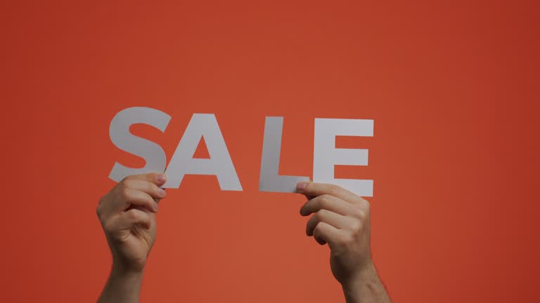 Sale announcement. Hands showing sale sign made of carved paper. Store discounts. Cheap shopping concept