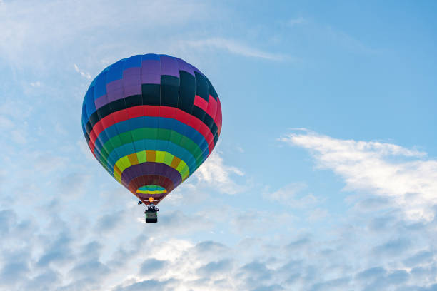 istock Multicolored hot air balloon on blue cloudy sky background 1328395925