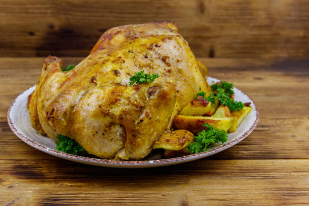 istock Baked whole chicken with potato on a wooden table 1328398880