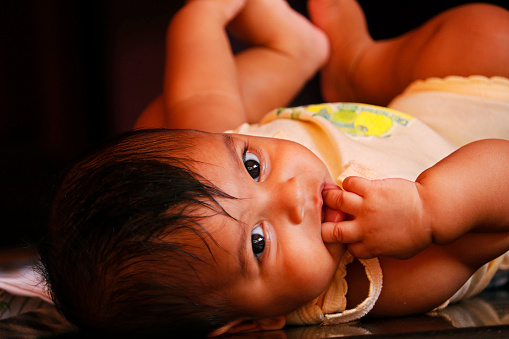cute indian baby boy lying on the floor with lovely smile in close up