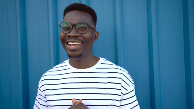 Young, cheerful black man on blue door background