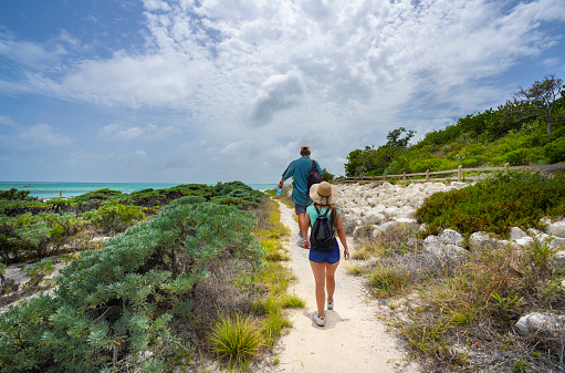 Couple walking to the beach with sand dunes. People hiking on Beautiful Florida beach. Bahia Honda State Park, Florida Keys, FLorida,USA.