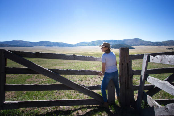 Cowgirl Lifting Old-Fashioned Wood Ranch Gate