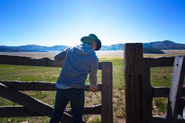 cowboy lifting old-fashioned wood ranch cercando puerta - cowboy blue meadow horizontal fotografías e imágenes de stock