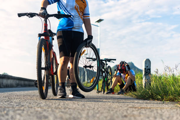 istock woman cycling has a problem during the way needs flat tire repairing,helping by bicycle mate takes wheel 1328414736