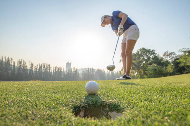 mujer asiática acción del golfista para ganar después de poner largo la bola de golf en el golf verde. hora de la mañana. - practicing golf putting golf flag fotografías e imágenes de stock