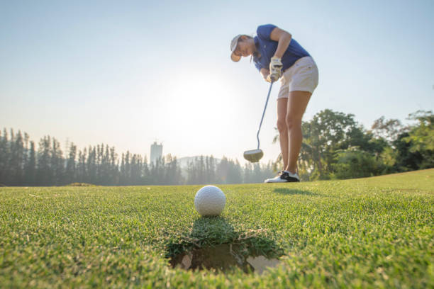 アジアの女性ゴルファーアクションは、長い緑のゴルフにゴルフボールを置いた後に勝つために。朝の時間。 - putting green practicing putting flag ストックフォトと画像