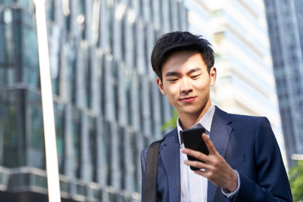 istock young asian business man office worker looking at mobile phone while walking on street 1328416564
