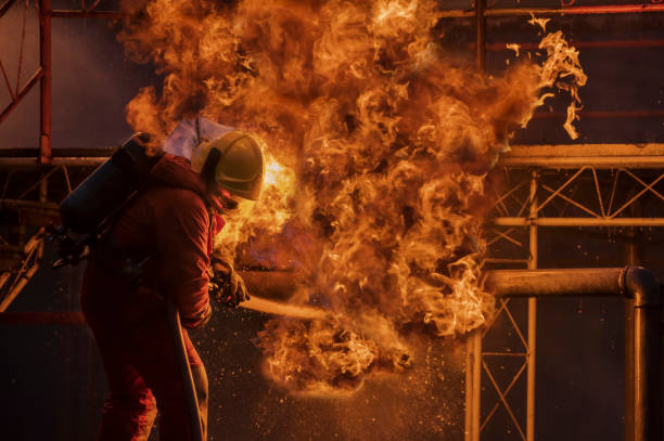 istock Firefighter in the training with fire hose nozzle spraying high pressure water to fire, Firefighter wearing a fire suit for safety under the danger case 1328426280