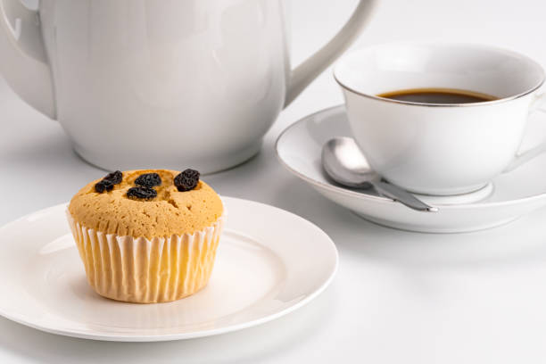 istock Side view of simply breakfast with raisin sponge cupcake in white ceramic dish. 1328427041