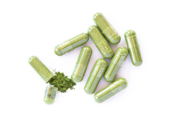 capsula di polvere di erbe verdi isolata su bianco - chinese medicine herb pill nutritional supplement foto e immagini stock
