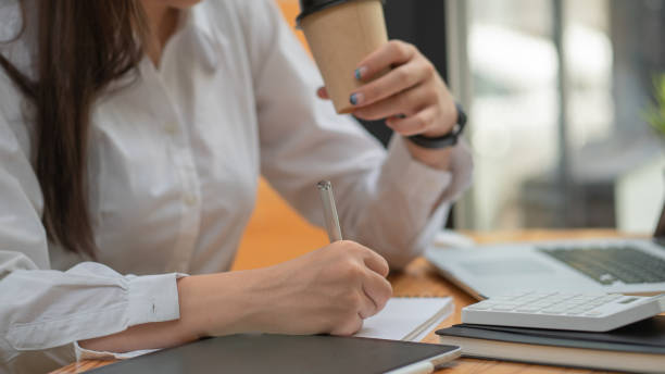 istock Close up hand's businesswoman doing an assignment while drinking coffee at cafe co-working space 1328433573
