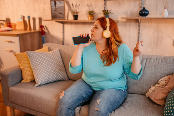 istock Woman holding phone singing and dancing at home 1328435220