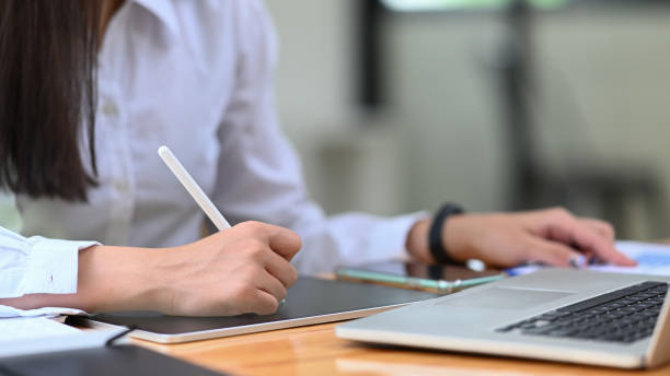 istock Female office worker holding stylus pen writing information on digital tablet. 1328441780