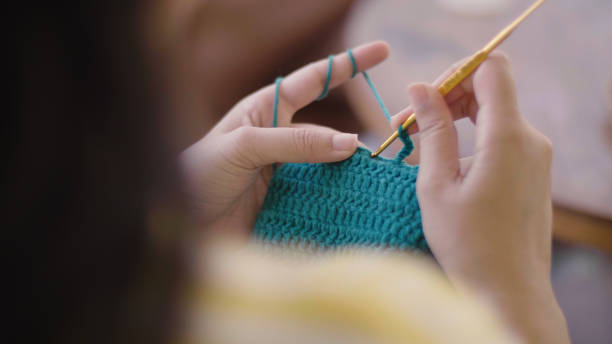 View of woman's hands knitting with green yarn for bag.  ,Thailand, real time, lifestyles ,diy ,Knitting ,Hobbies ,crochet , Learning a hobby, enjoying relaxation, looking happy, lifestyle concept