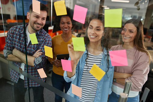 Group of web designers using sticky notes on a glass wall during a meeting
