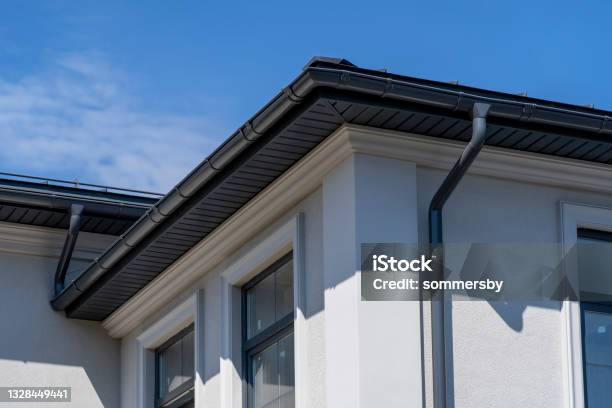 Corner Of House With Windows New Gray Metal Tile Roof And Rain Gutter Metallic Guttering System Guttering And Drainage Pipe Exterior Stock Photo - Download Image Now