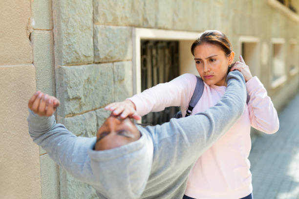 Young Hispanic woman defending against thief attack outdoors Young Hispanic woman defending against thief attack outdoors, using basic self-defense techniques self defense stock pictures, royalty-free photos & images