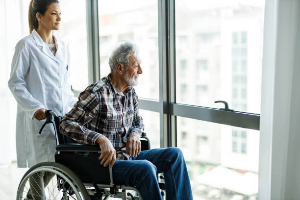 istock Disabled mature man and his caregiver looking through window at home. 1328450558