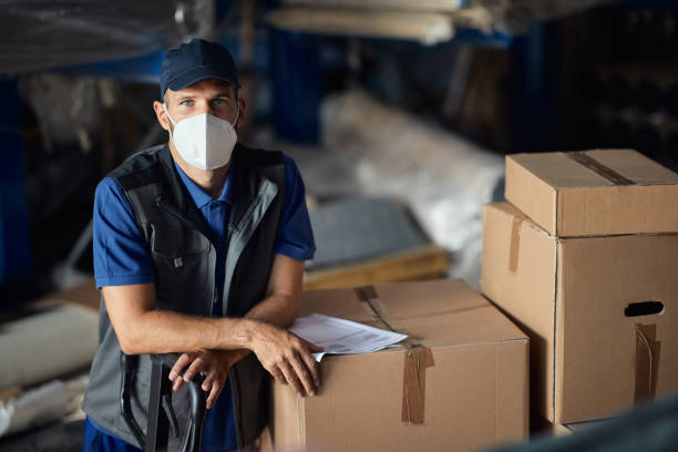 istock Portrait of male worker wearing protective face mask while working at distribution warehouse. 1328450797