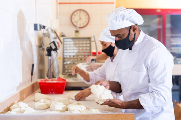 istock Male and female baker in protective mask working together in bakery 1328451720