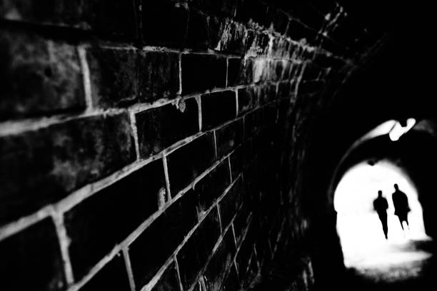 istock Silhouette of two people at the exit of a brick tunnel 1328458278