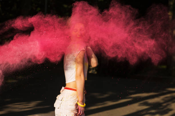 istock Attractive young woman playing with pink dry paint Holi exploding around her 1328461267